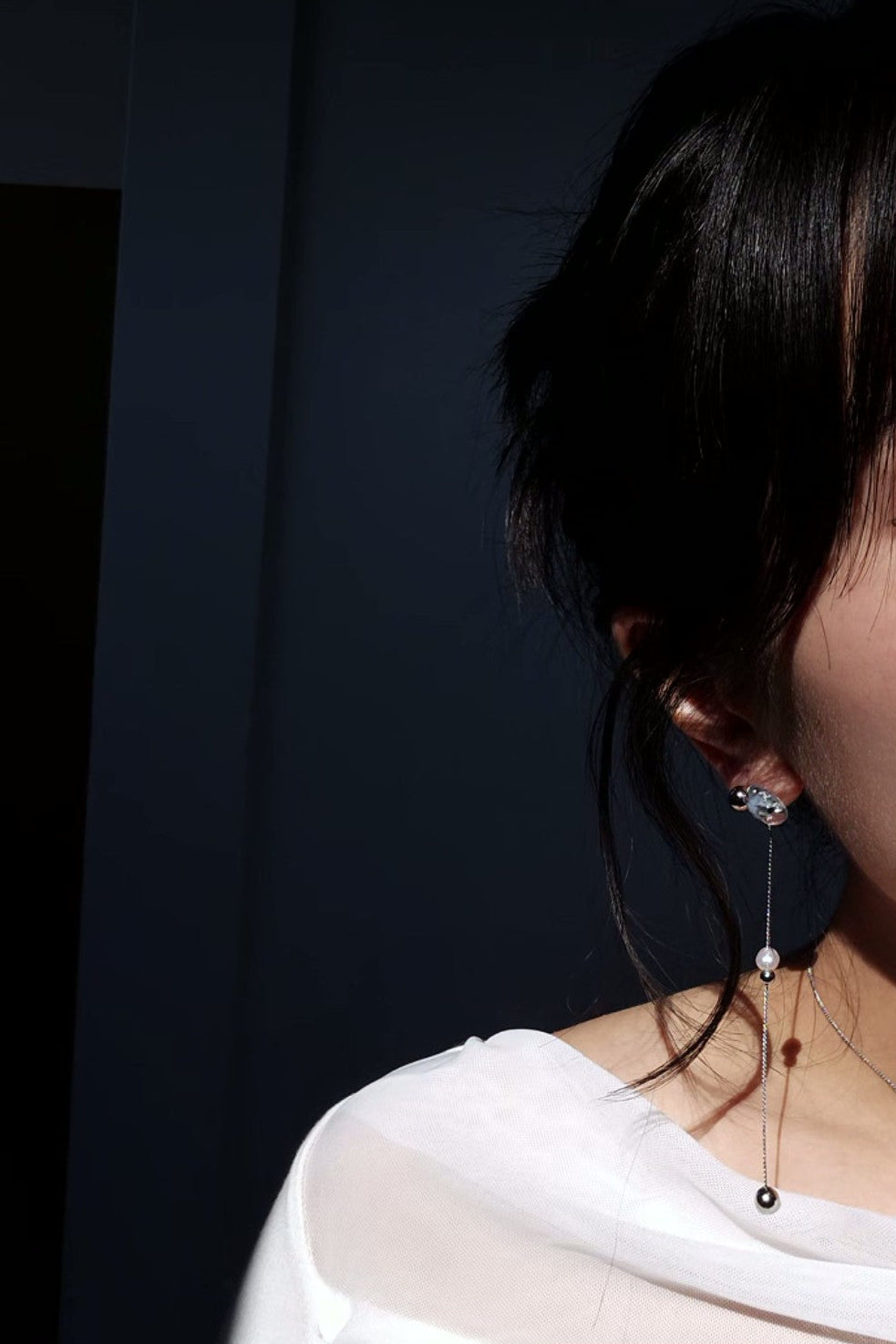 Model wearing NAMI multiway drop earring showcasing detachable chain, freshwater pearl, and fluid silvery-blue glow