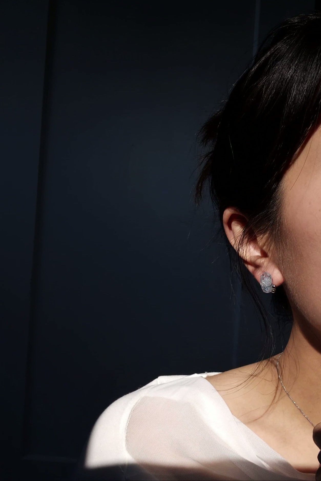 Model wearing NAMI stud earring with silvery-blue hand-molded stone and three tiny silver orbs.