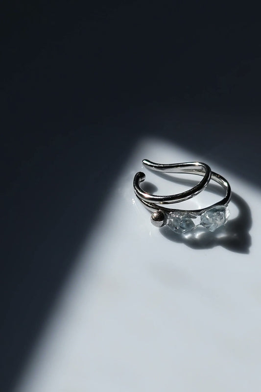 NAMI silver teardrop ear cuff with two silvery blue-gray hand-molded stones and tiny silver orb, wave-inspired design.