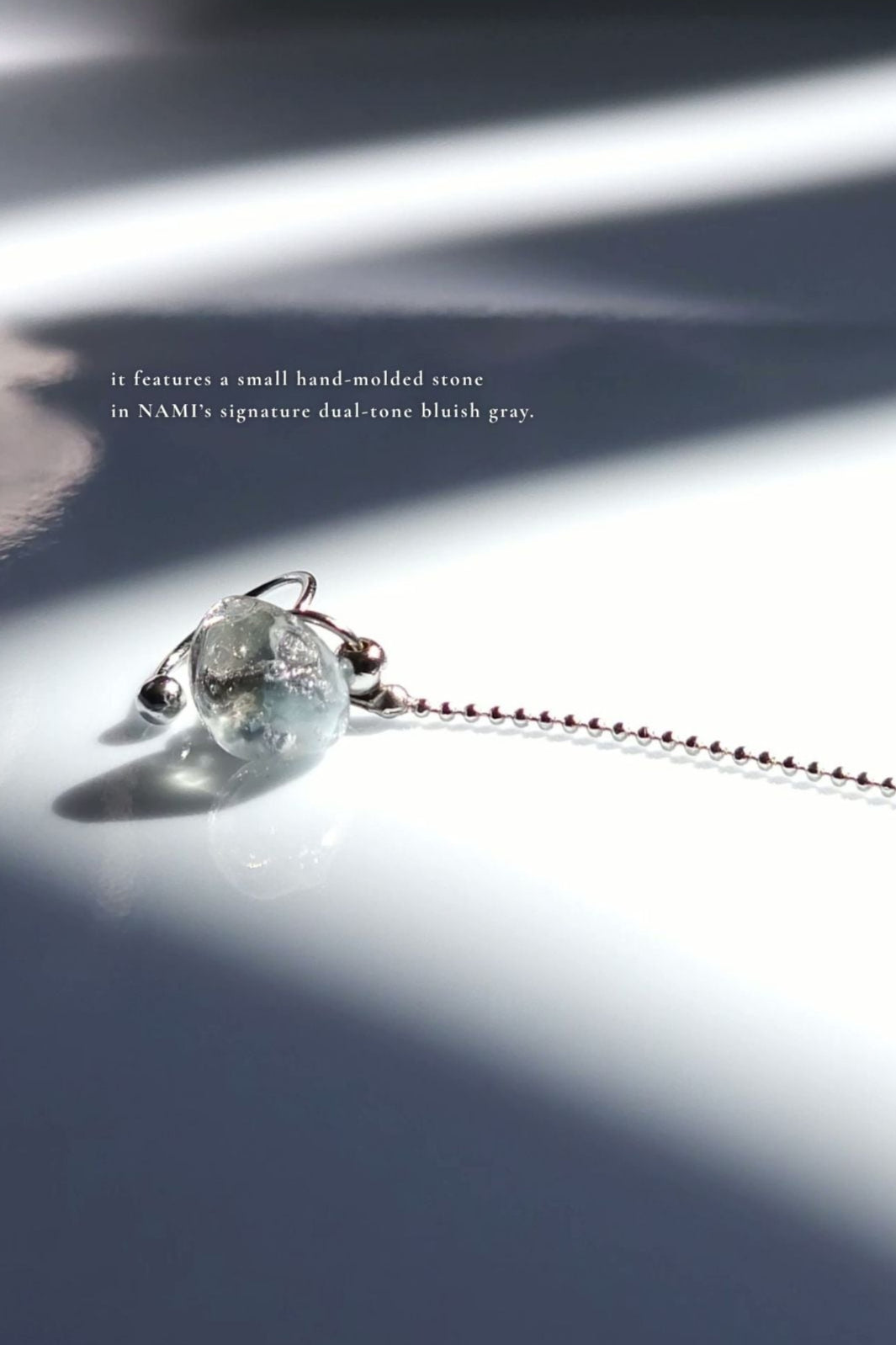 Close-up of NAMI multiway chain ear cuff with hand-molded silvery-blue stone and detachable chain, inspired by ocean waves, sculptural yet delicate.