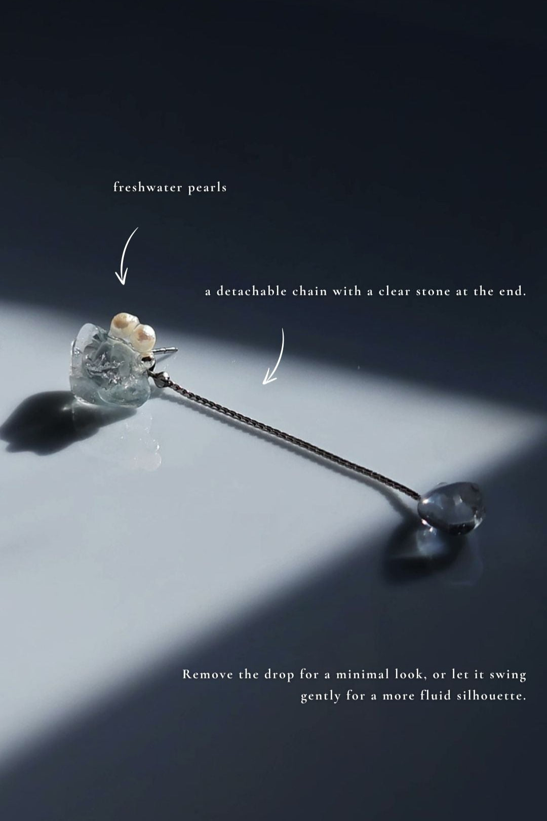 Flatlay of NAMI multiway short drop earring with pearls, silvery-blue stone, and removable chain for minimal or fluid styling.