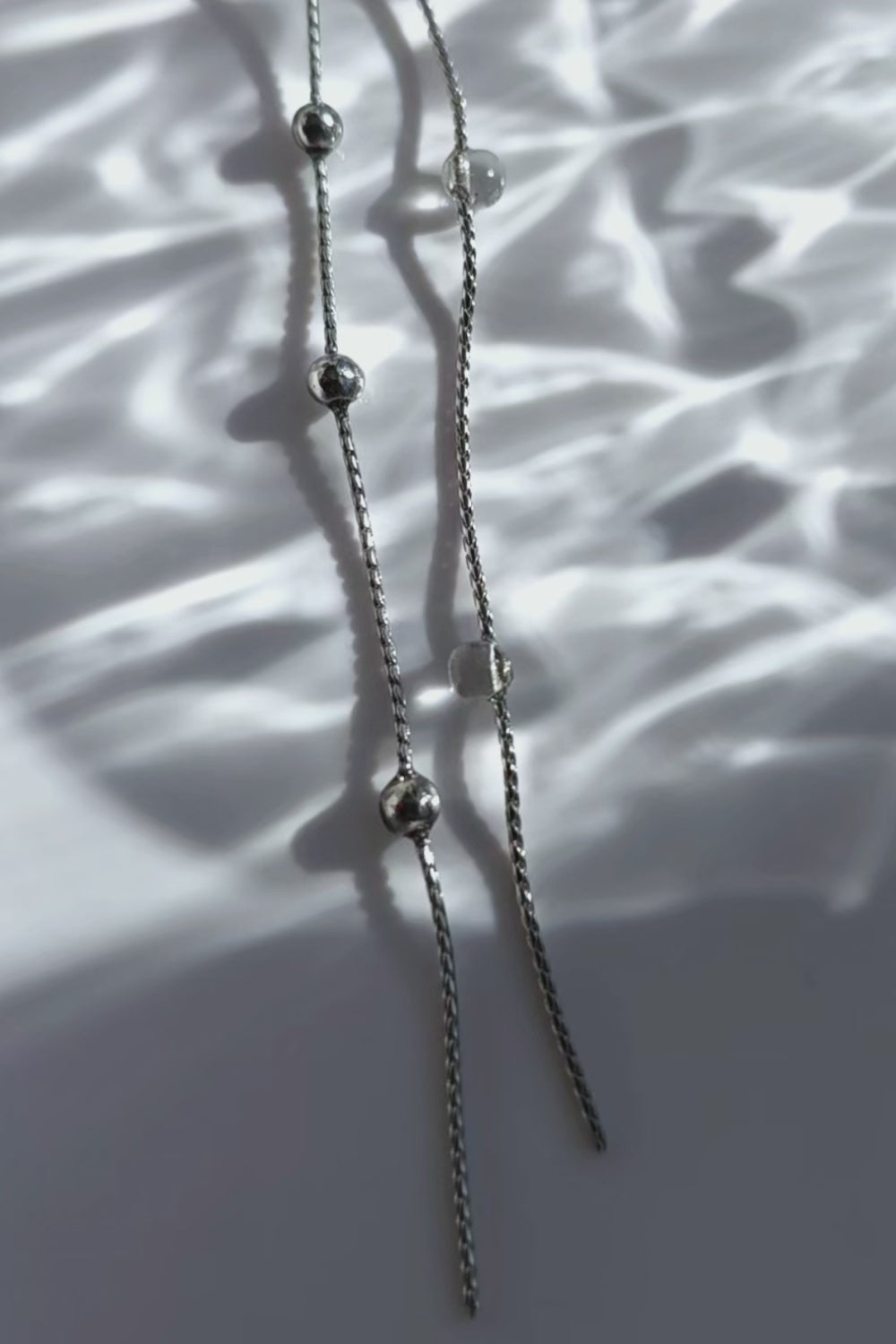 A video of the HISEN silver multiway drop earring with clear orb and silver chain strands, versatile as stud, drop, or dramatic style.