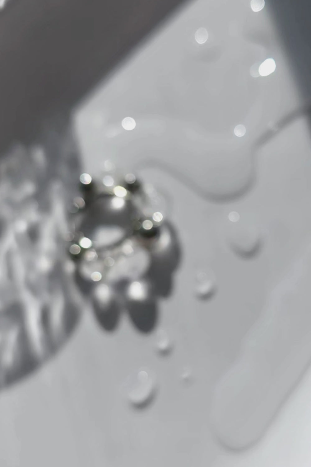 Close-up video of GINRO hoop earring showing clear and silver orbs in quiet, balanced design inspired by shimmering frozen dew.
