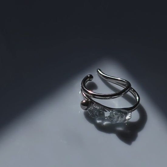 close-up video of the NAMI silver teardrop ear cuff with two silvery blue-gray hand-molded stones and tiny silver orb, wave-inspired design.