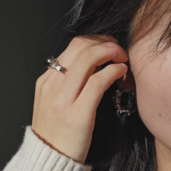 A video of a model wearing GINRO earring with silver orb facing front, styled with RYU reversible ear cuff.
