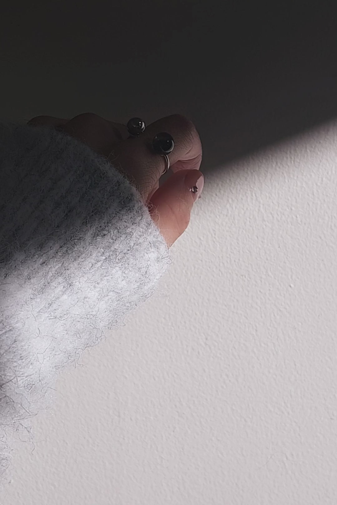 Close-up of a hand wearing double orb ring, KAGE double ring, on index finger and showcasing how the tone changes from translucent black to deep black.