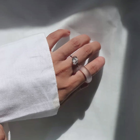 REI ring worn on middle finger, a simple, minimal band with a subtle shimmering centerpiece inspired by melting ice.