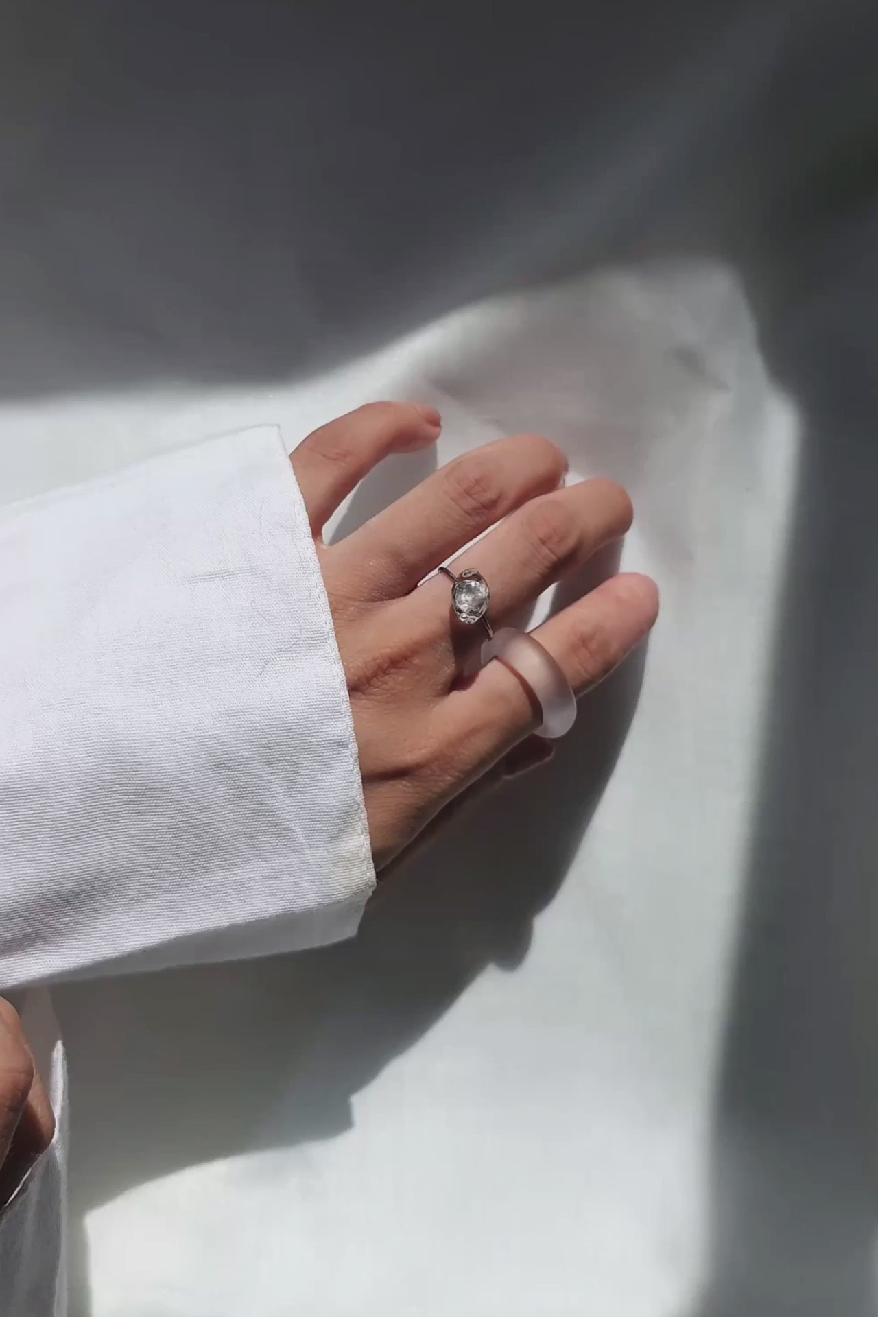 REI ring worn on middle finger, a simple, minimal band with a subtle shimmering centerpiece inspired by melting ice.