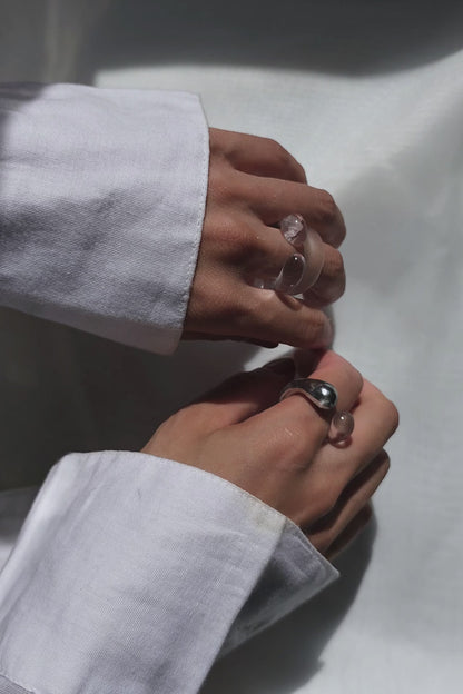 REI square ring worn on finger, minimal yet bold with its hand-molded square shape and shimmering contrast of silver and translucent textures.