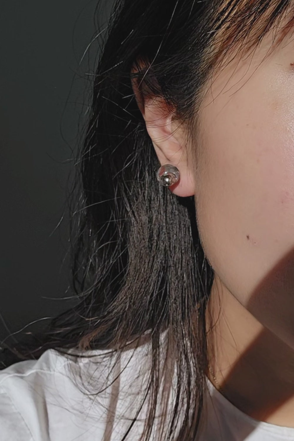 TSUYU silver stud earring on model, inspired by morning dew, with reflective clear and silver tones that shift with light.