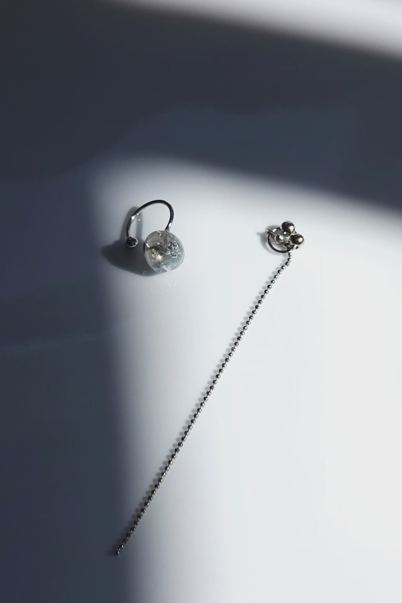 Close-up video of NAMI multiway chain ear cuff with hand-molded silvery-blue stone and detachable chain, inspired by ocean waves, sculptural yet delicate.