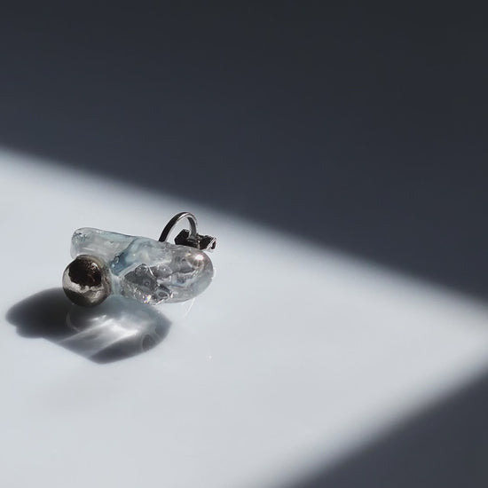 Close-up video of the NAMI ear climber with hand-molded silvery blue-gray stone and silver orb, inspired by waves.