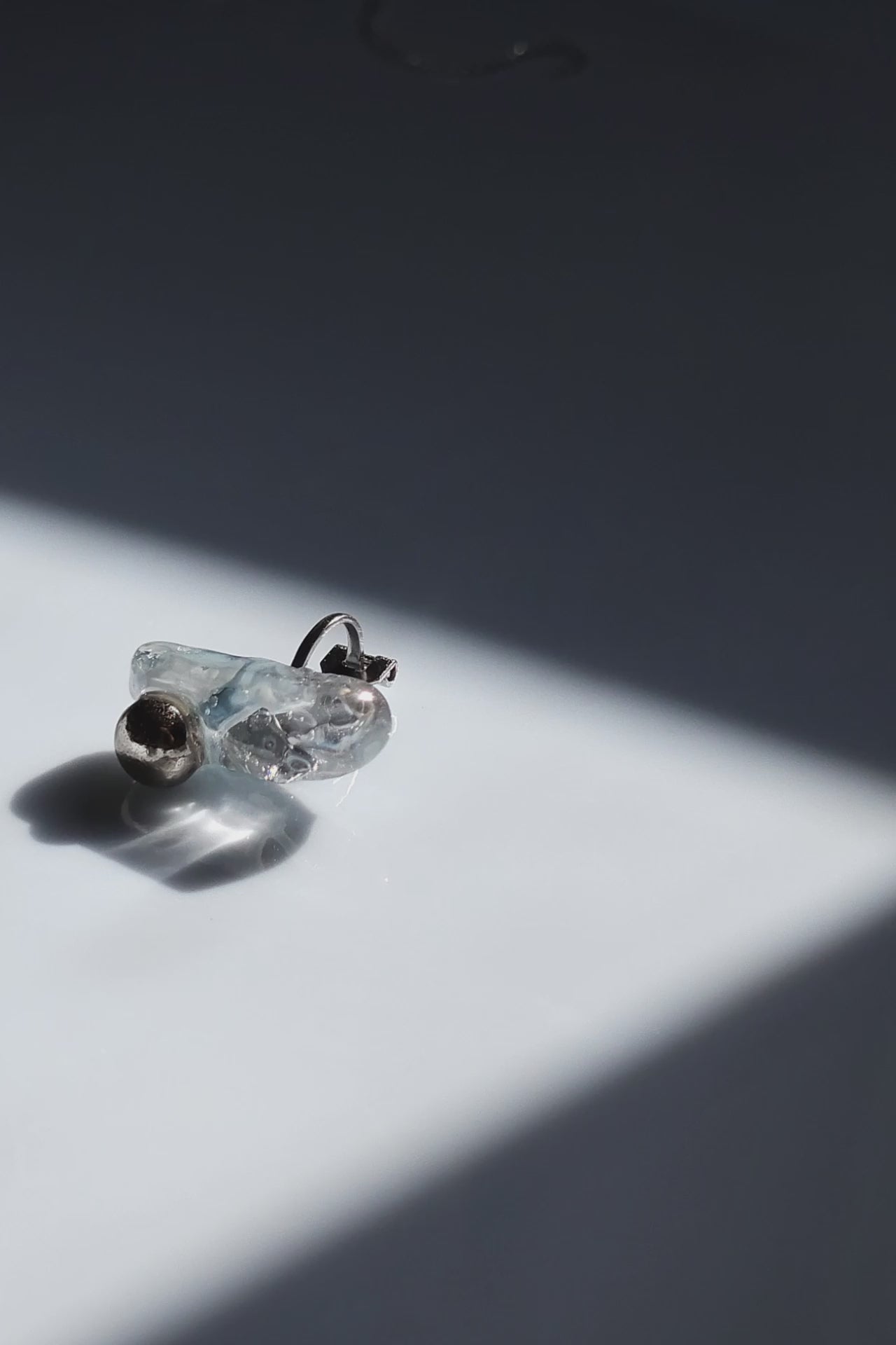 Close-up video of the NAMI ear climber with hand-molded silvery blue-gray stone and silver orb, inspired by waves.