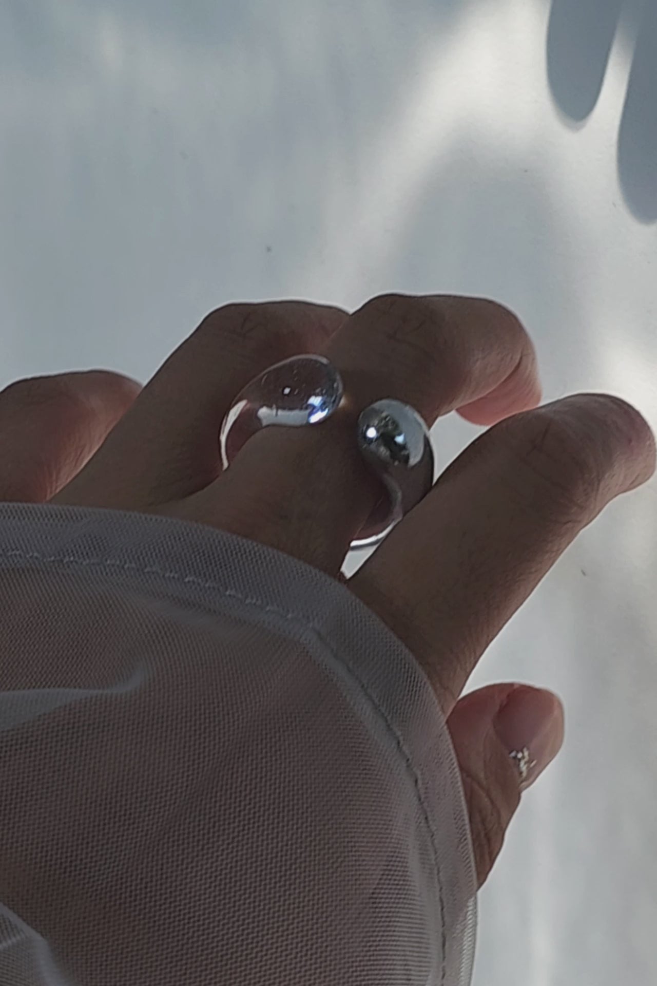 Model wearing TORORI silver as a ring, showcasing sculptural dripping water-inspired design with clear resin details.
