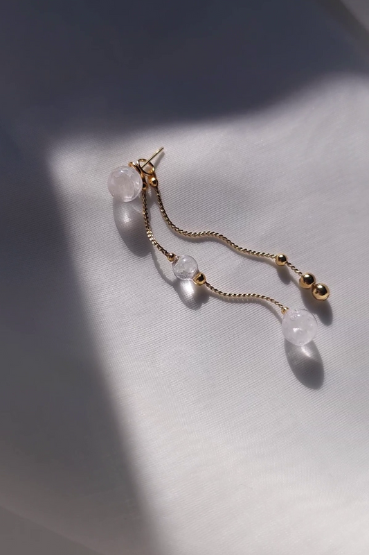 REI gold short drop with gold chain and clear orbs on a light background