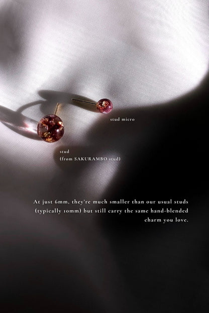 A 6mm micro stud in dark cherry tone, SAKRUAMBO micro stud is compared with a 10mm stud in dark cherry, SAKURAMBO stud on a flat surface.