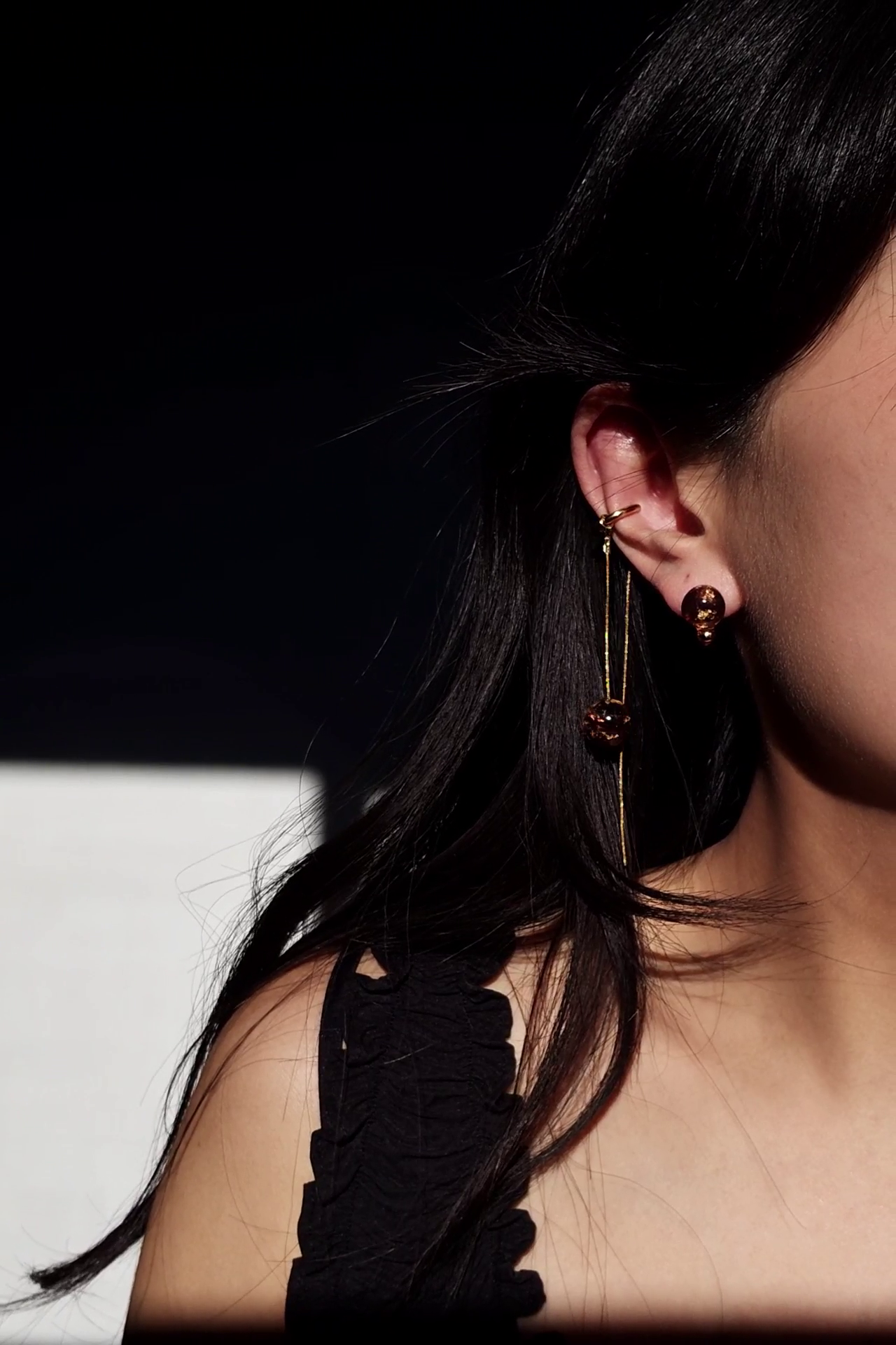 Model wearing only the stud part of short orb drop in dark cherry, SAKURAMBO short drop, paired with gold chain ear cuff with orb in dark cherry, SAKURAMBO chain ear cuff.