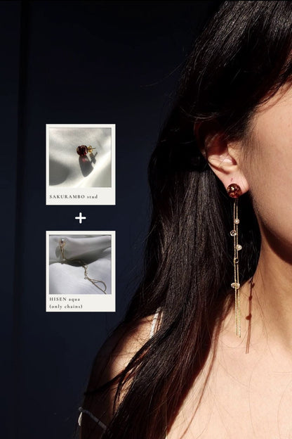 Close-up of a woman wearing a dark cherry stud, SAKURAMBO stud, paired with gold chains from HISEN aqua