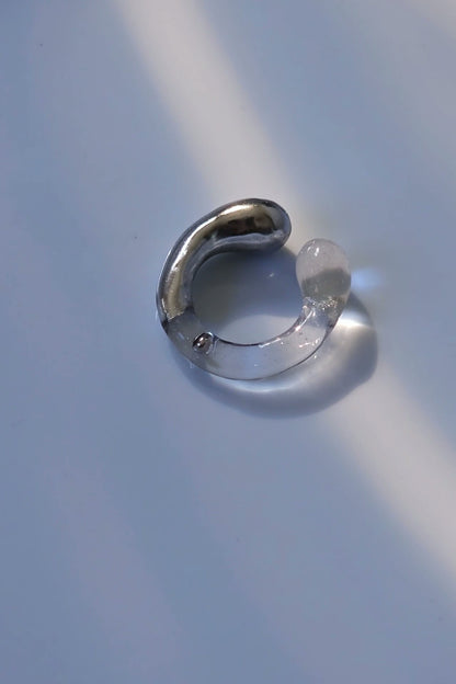 TORORI silver multiway ring with sculptural clear design, inspired by dripping water, shown laid on neutral background.
