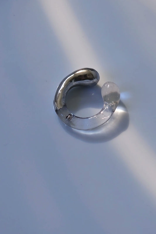 TORORI silver multiway ring with sculptural clear design, inspired by dripping water, shown laid on neutral background.