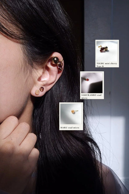 Close-up of a person wearing TSUBU mini dark cherry on the helix with micro studs from SAKURAMBO dark cherry series and HARU orange series