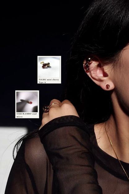 Model wearing a 6mm stud in dark cherry, SAKURAMBO micro stud with an ear cuff in the same dark cherry tone, TSUBU mini cherry on a right ear.