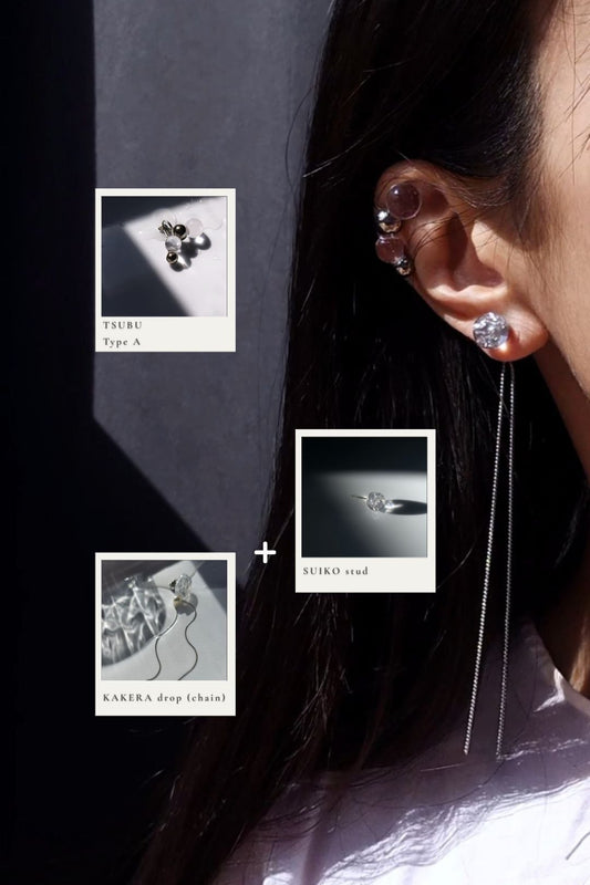 Model wearing clear and silver earring pieces, SUIKO stud with the chain from KAKERA multiway drop on earlobe, and TSUBU on helix.
