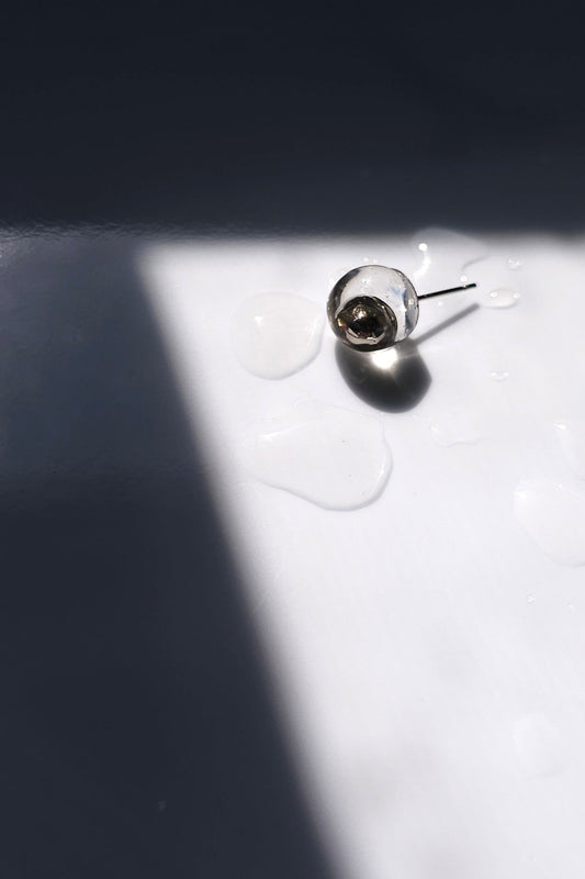TSUYU silver stud earring, inspired by morning dew, with reflective clear and silver tones that shift with light.