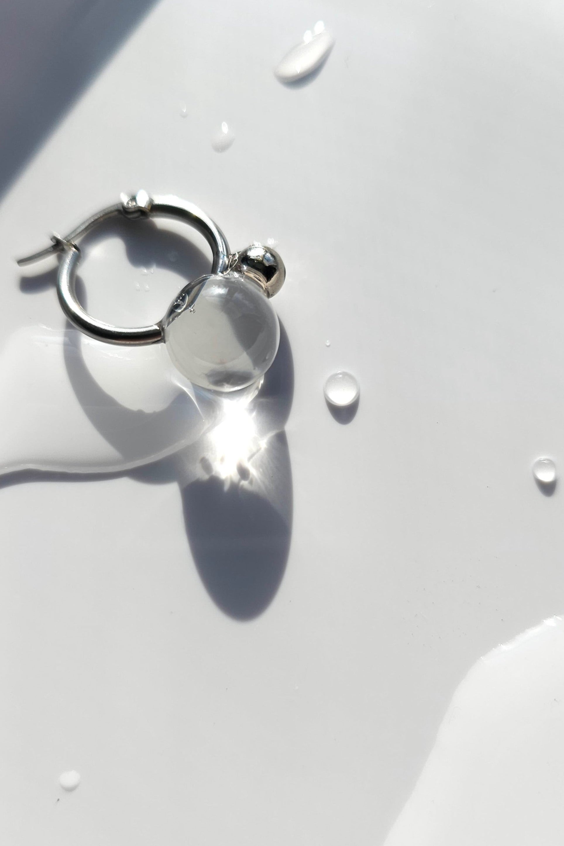 YOTSUYU silver earrings with translucent and clear orb on silver hoop, inspired by night dew under moonlight, lightweight and luminous huggie.